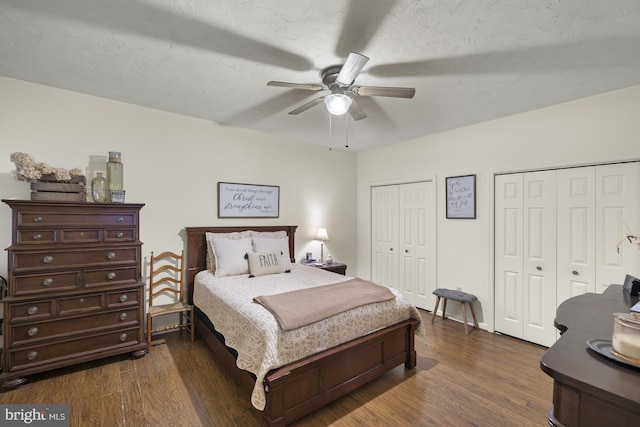 bedroom with ceiling fan, a textured ceiling, dark wood finished floors, and multiple closets