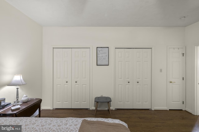 bedroom with multiple closets, baseboards, and wood finished floors