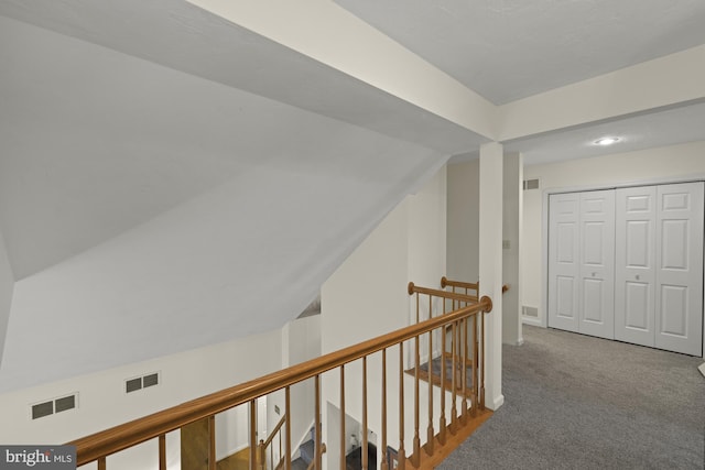 corridor featuring visible vents, carpet flooring, and an upstairs landing