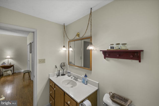 bathroom with toilet, vanity, hardwood / wood-style flooring, and baseboards