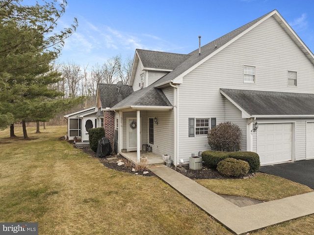 view of front of property featuring a garage, a front lawn, a shingled roof, and aphalt driveway