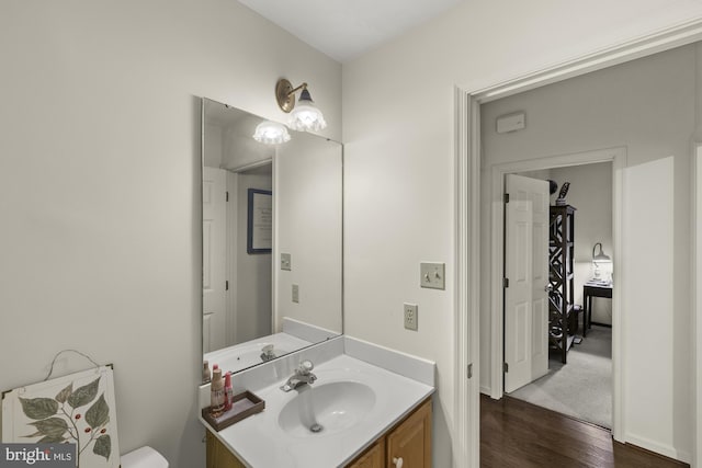 half bathroom with toilet, wood finished floors, and vanity