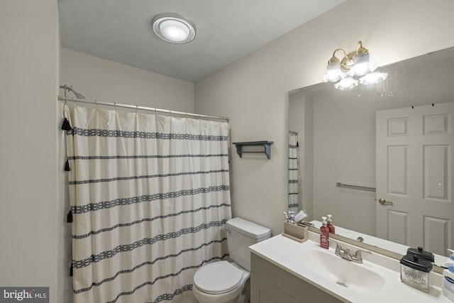 bathroom featuring curtained shower, vanity, and toilet