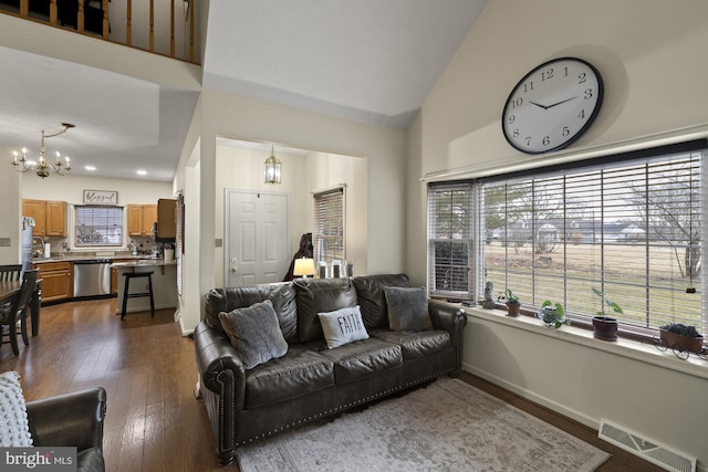 living room featuring visible vents, baseboards, dark wood-type flooring, high vaulted ceiling, and a notable chandelier