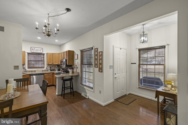 kitchen featuring dark wood finished floors, baseboards, stainless steel appliances, and a notable chandelier