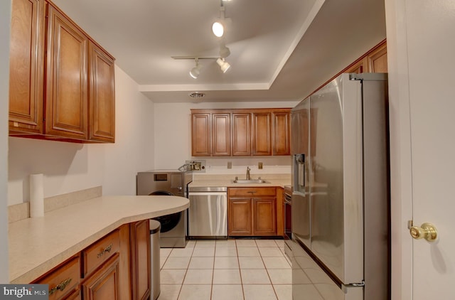 kitchen with light countertops, brown cabinets, light tile patterned flooring, stainless steel appliances, and a sink