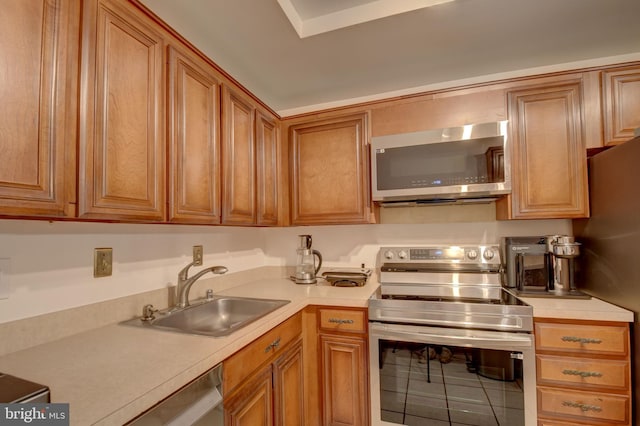 kitchen featuring light countertops, brown cabinets, appliances with stainless steel finishes, and a sink