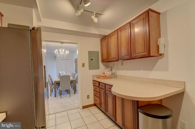 kitchen with electric panel, brown cabinets, light countertops, and freestanding refrigerator