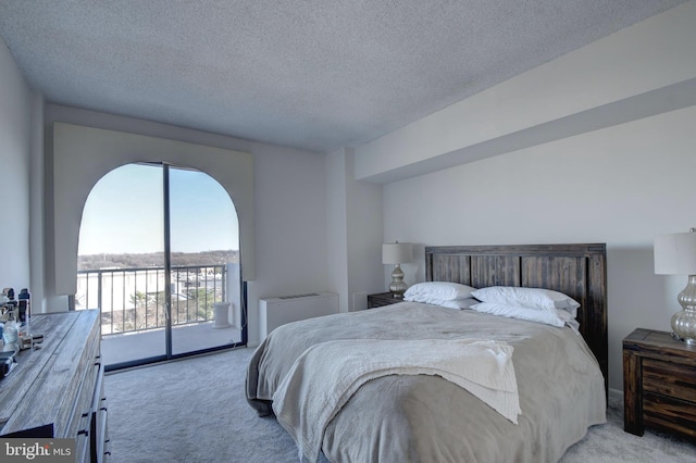 carpeted bedroom featuring a textured ceiling and access to outside