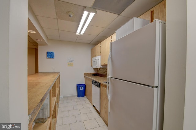 kitchen with white appliances, light tile patterned flooring, a paneled ceiling, and light countertops