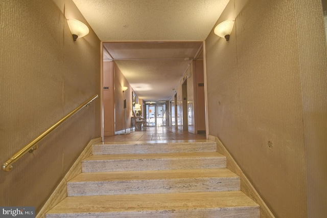 staircase with baseboards and a textured ceiling