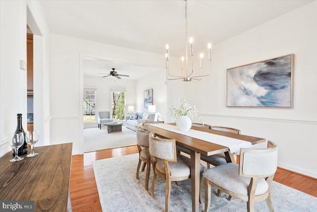 dining space featuring light wood-style floors and ceiling fan with notable chandelier