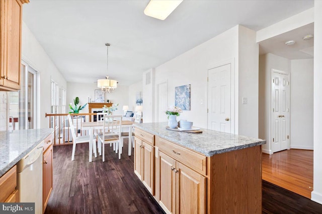 kitchen featuring light stone counters, a kitchen island, dark wood-style flooring, dishwasher, and decorative light fixtures