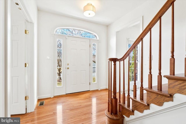 foyer with stairs, visible vents, and light wood finished floors