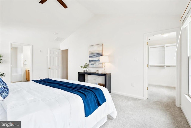 bedroom featuring a spacious closet, connected bathroom, baseboards, carpet, and vaulted ceiling