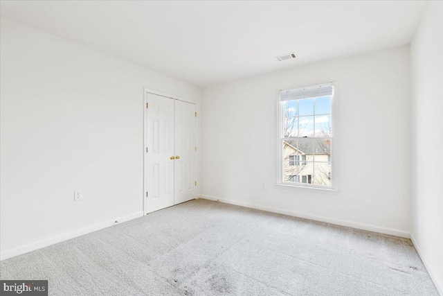 carpeted spare room featuring visible vents and baseboards