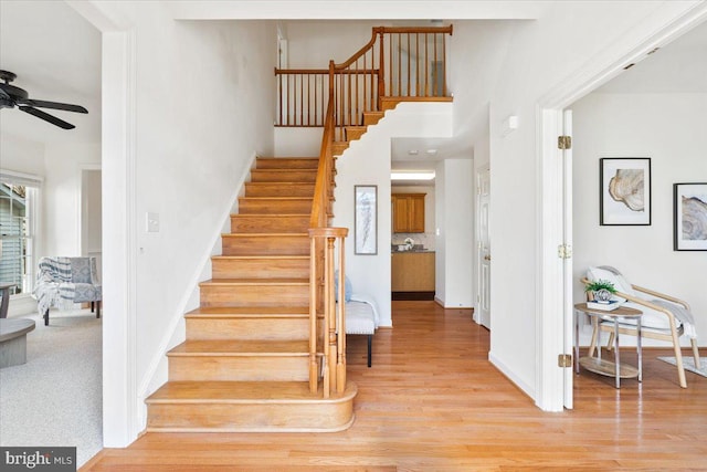 stairway featuring baseboards, ceiling fan, and wood finished floors