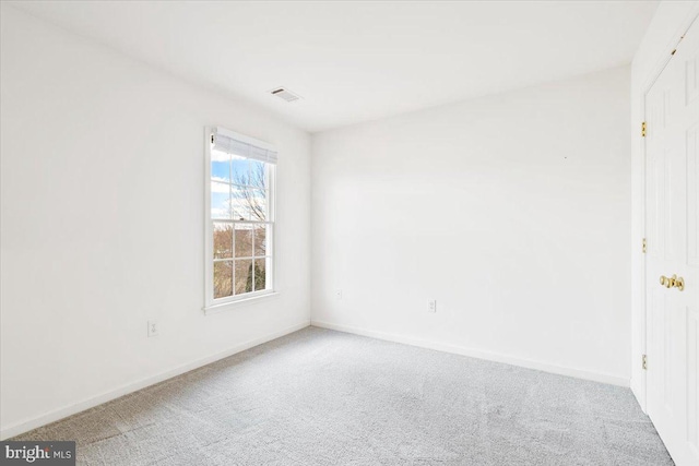 carpeted spare room with visible vents and baseboards