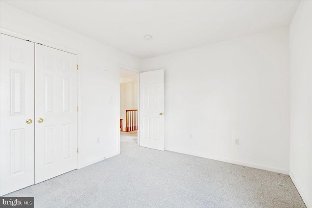 unfurnished bedroom featuring a closet, baseboards, and carpet