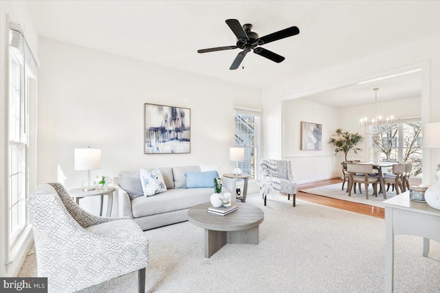 living room with ceiling fan with notable chandelier, wood finished floors, and a healthy amount of sunlight