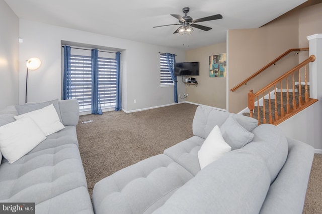 carpeted living area with stairs, baseboards, and a ceiling fan