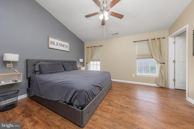 bedroom featuring visible vents, lofted ceiling, baseboards, and wood finished floors