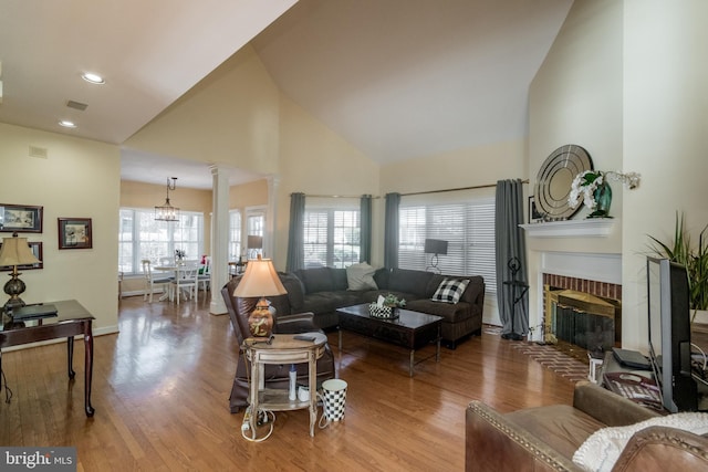 living room featuring visible vents, a fireplace, wood finished floors, and decorative columns