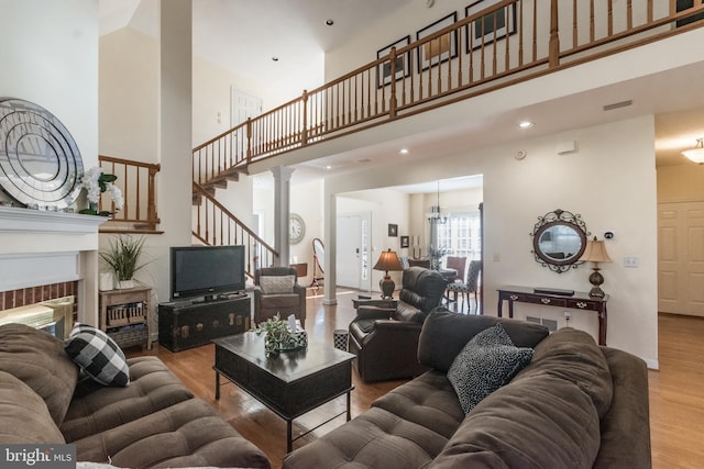 living area featuring wood finished floors, a high ceiling, recessed lighting, a fireplace, and stairs