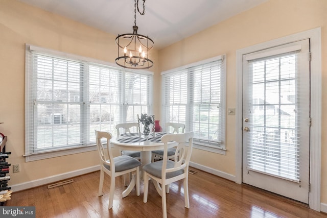 dining area with a notable chandelier, plenty of natural light, and wood finished floors