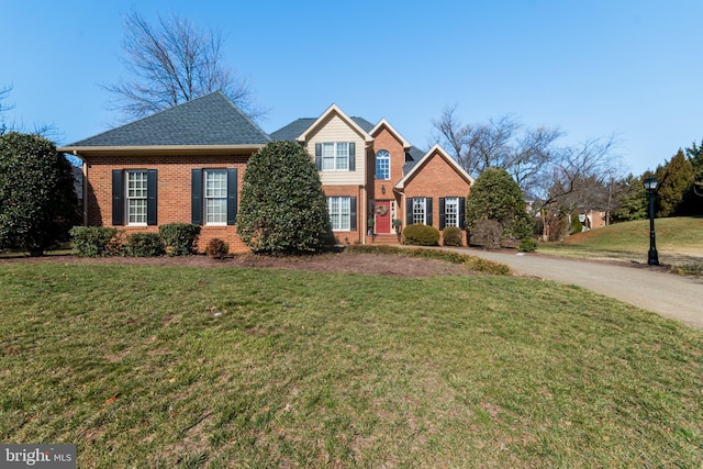 traditional home with a front yard, brick siding, and a shingled roof