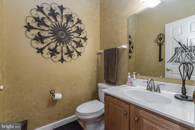 bathroom with vanity, toilet, and baseboards