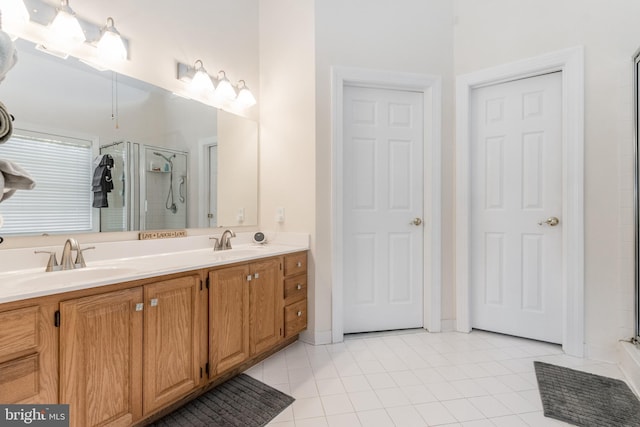 bathroom featuring a shower stall, double vanity, tile patterned floors, and a sink