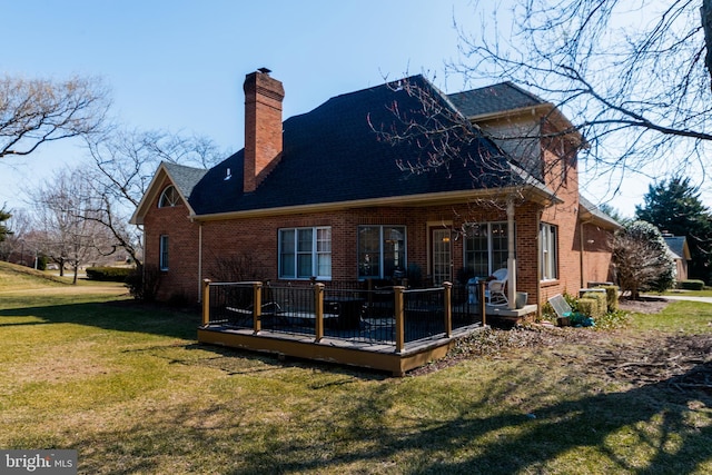 rear view of property with a deck, a lawn, brick siding, and a chimney