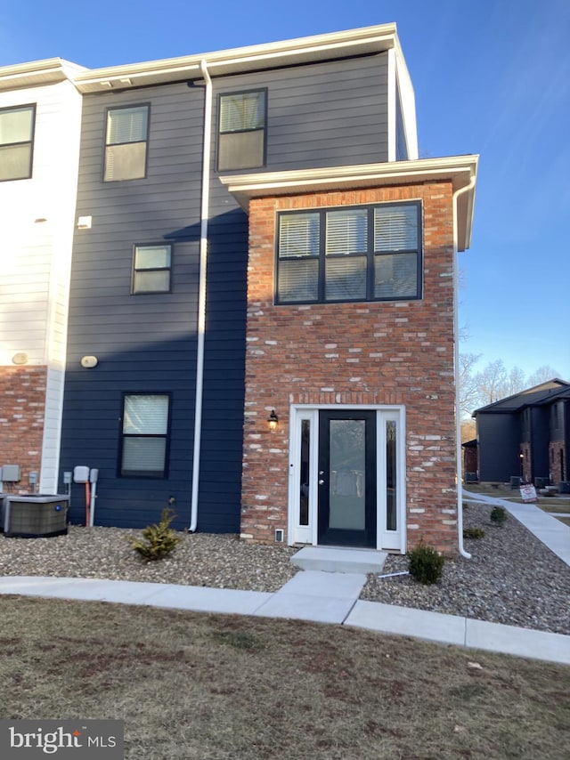 view of front of home with central AC and brick siding