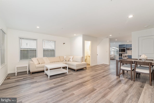 living area featuring recessed lighting, baseboards, and light wood finished floors