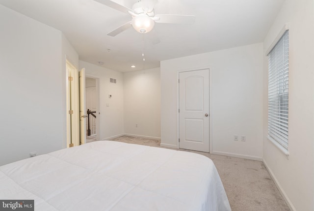 bedroom with a ceiling fan, visible vents, light carpet, and baseboards