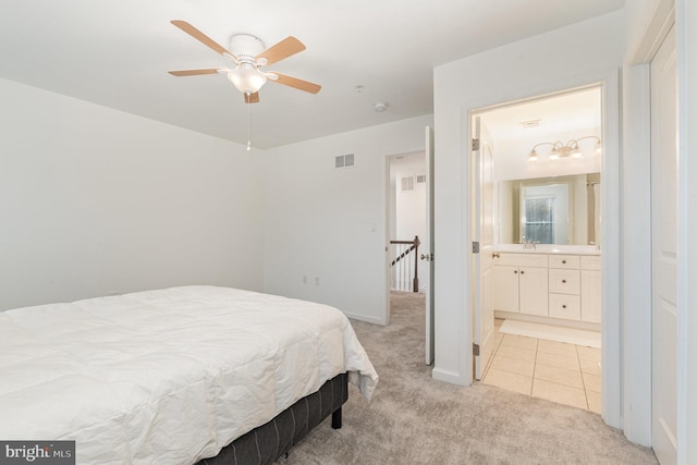 bedroom with visible vents, light carpet, light tile patterned flooring, ensuite bath, and baseboards