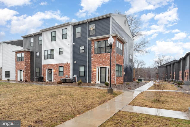 view of property with brick siding and a front lawn