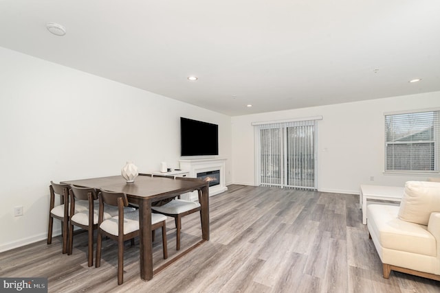 dining room with recessed lighting, baseboards, wood finished floors, and a glass covered fireplace