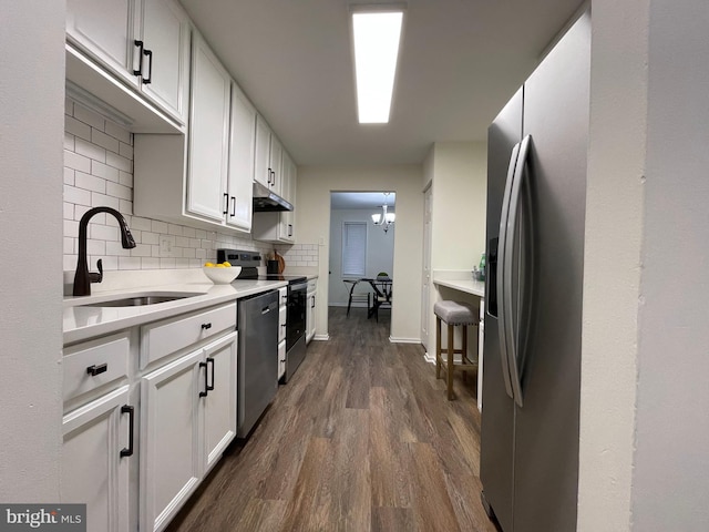 kitchen with dark wood-style flooring, tasteful backsplash, appliances with stainless steel finishes, a sink, and under cabinet range hood