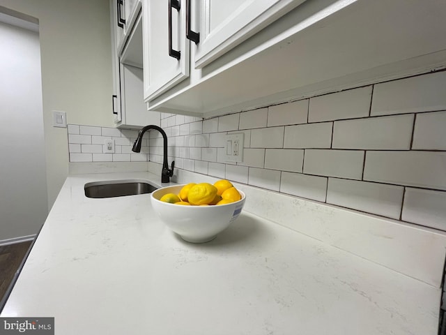 details featuring tasteful backsplash, white cabinetry, and a sink