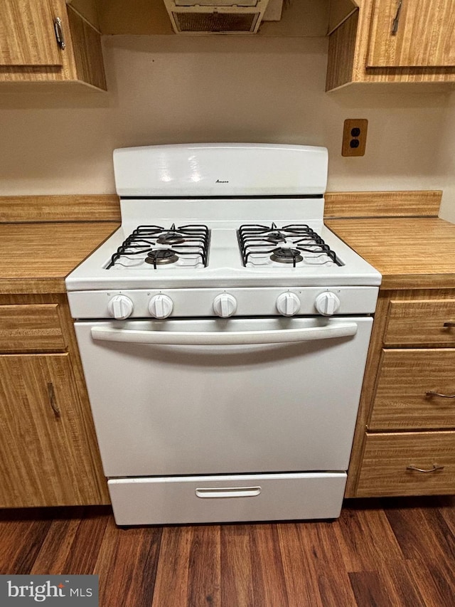 kitchen featuring dark wood-style flooring, brown cabinets, gas range gas stove, and light countertops