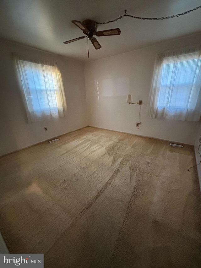 empty room with ceiling fan, carpet, and visible vents