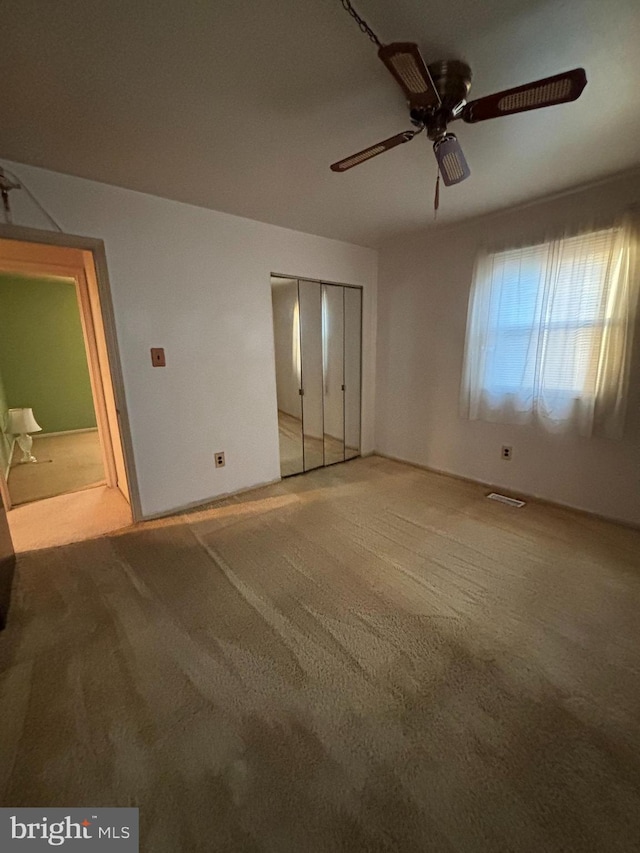 unfurnished bedroom featuring carpet floors, a closet, visible vents, and a ceiling fan