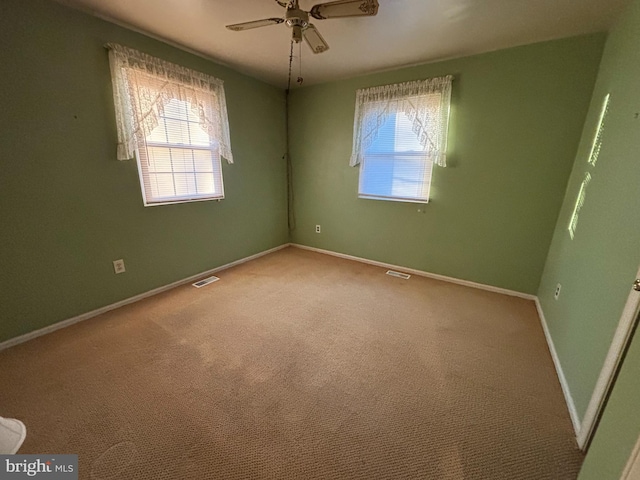 carpeted empty room with baseboards, visible vents, and ceiling fan