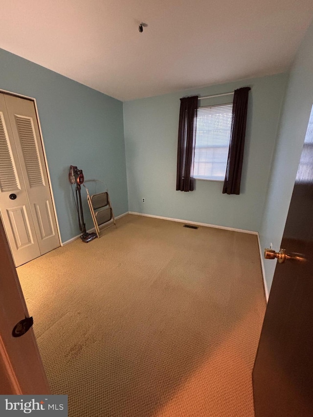 unfurnished bedroom with carpet floors, a closet, visible vents, and baseboards