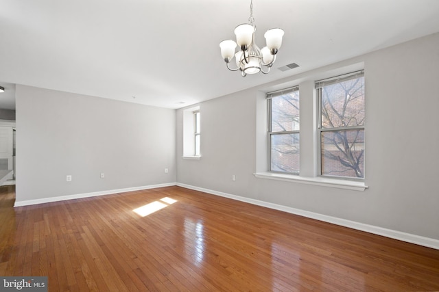 unfurnished dining area featuring a chandelier, wood-type flooring, visible vents, and baseboards