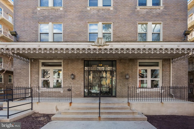 property entrance featuring a porch and brick siding