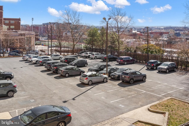 uncovered parking lot featuring fence and a city view