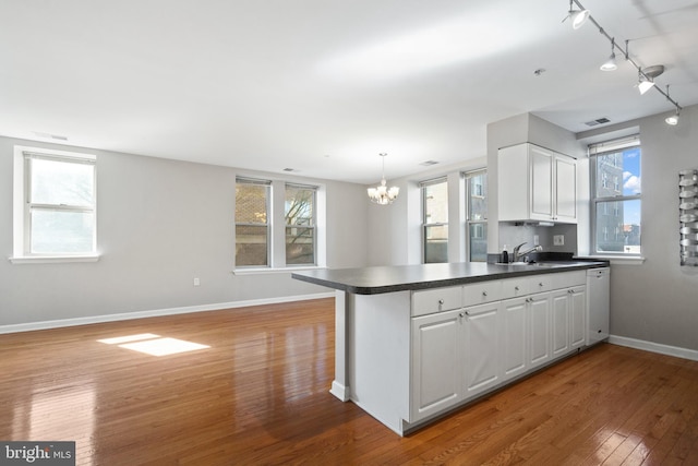 kitchen featuring light wood-style floors, dark countertops, white cabinets, and a peninsula